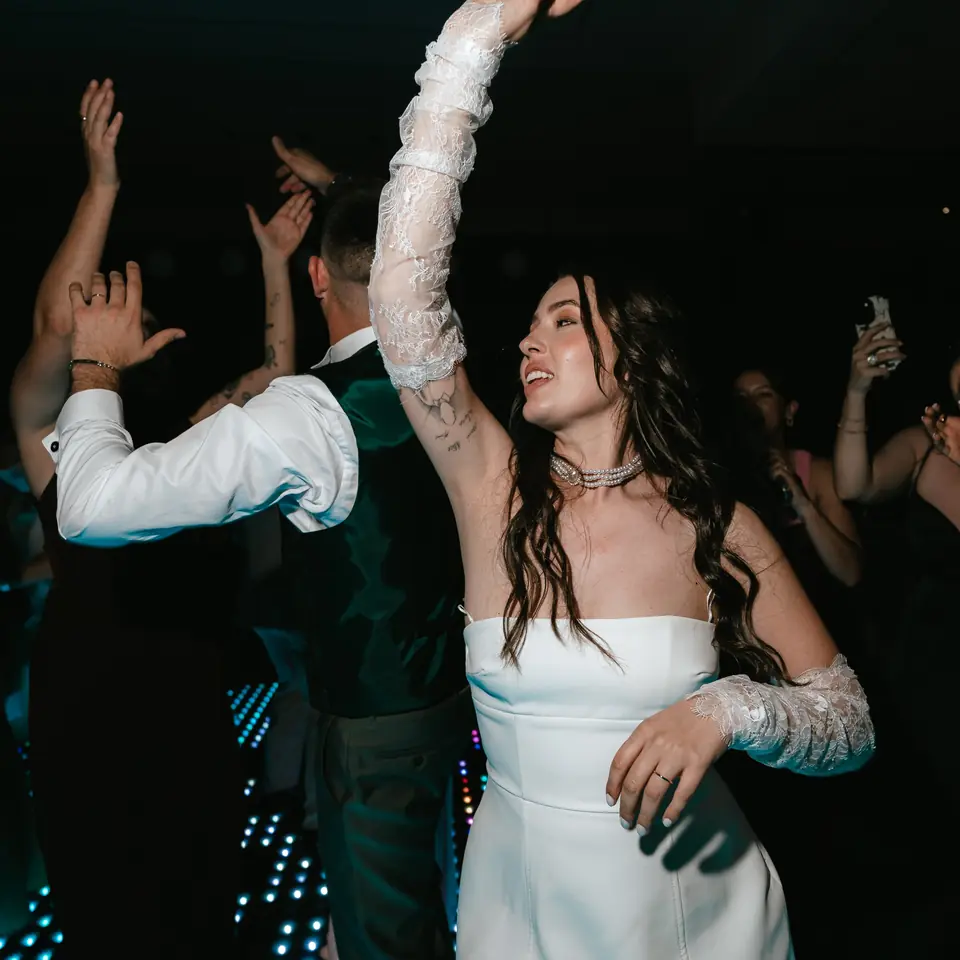 Noiva de braços no ar na pista de dança